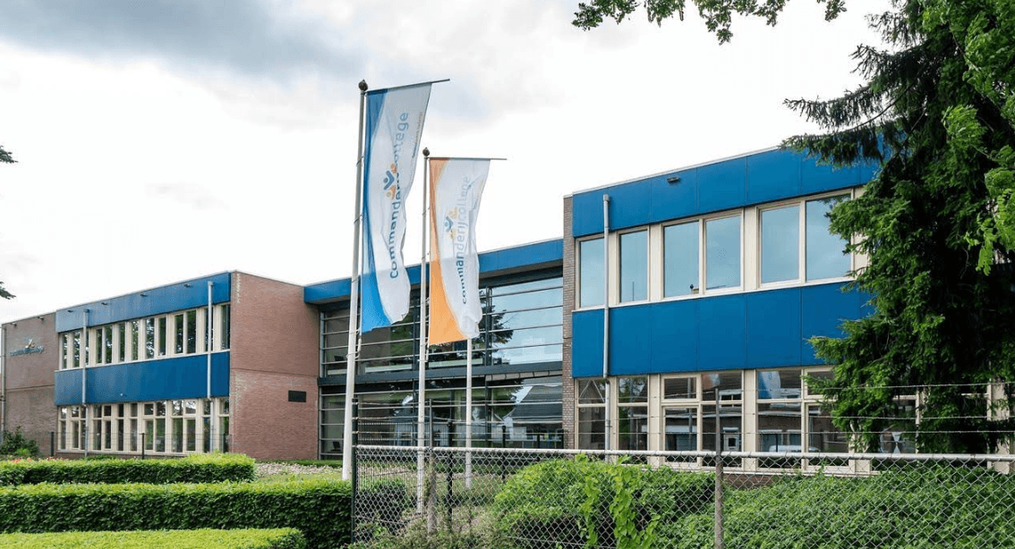 Bild vergrößern: Das Schulgebäude mit den Schulfahnen vor dem Gebäude.